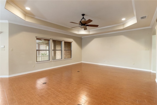 empty room with hardwood / wood-style floors, ceiling fan, a tray ceiling, and ornamental molding