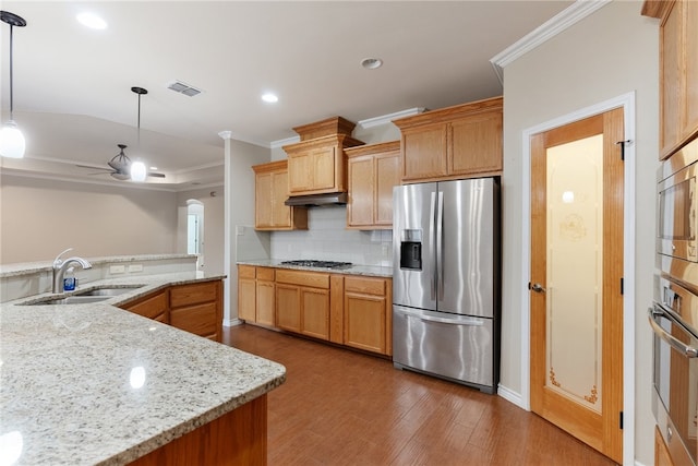 kitchen featuring wood-type flooring, light stone counters, stainless steel appliances, pendant lighting, and sink