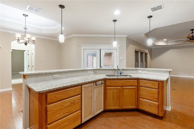 kitchen with sink, light hardwood / wood-style flooring, decorative light fixtures, and ornamental molding