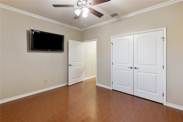 unfurnished bedroom featuring ceiling fan, ornamental molding, a closet, and wood-type flooring