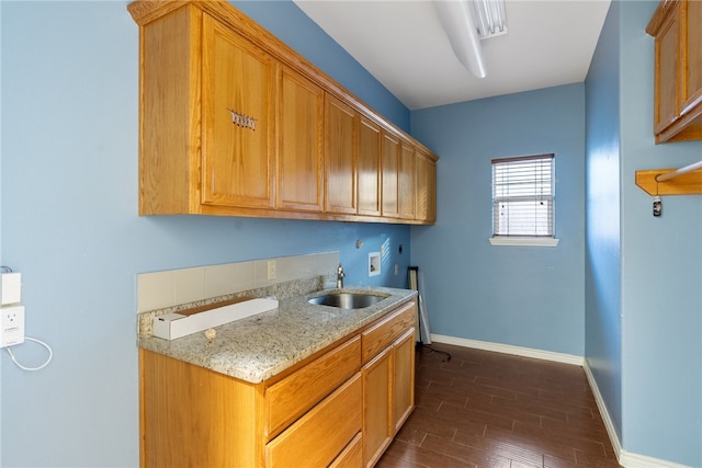 kitchen featuring sink, light stone counters, and dark hardwood / wood-style flooring