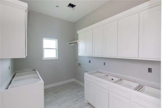 laundry area featuring hookup for an electric dryer, light hardwood / wood-style floors, hookup for a washing machine, and cabinets