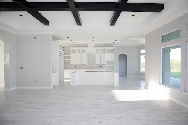 unfurnished living room featuring ornamental molding, beam ceiling, light wood-type flooring, and coffered ceiling