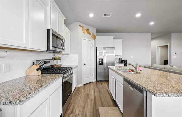 1293 Carnaby St, Corpus Christi, TX 78415 - kitchen featuring appliances with stainless steel finishes, wood finished floors, a center island with sink, decorative backsplash, and recessed lighting