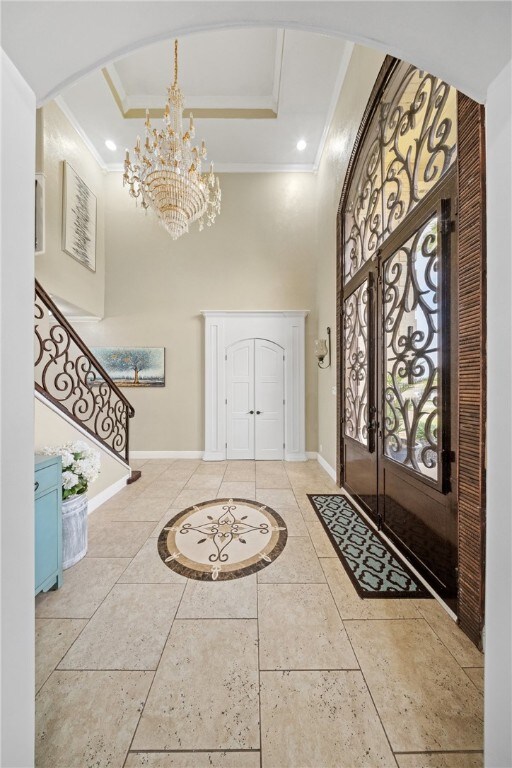 5413 King Trl, Corpus Christi, TX 78414 - foyer featuring ornamental molding, a high ceiling, a tray ceiling, baseboards, and arched walkways