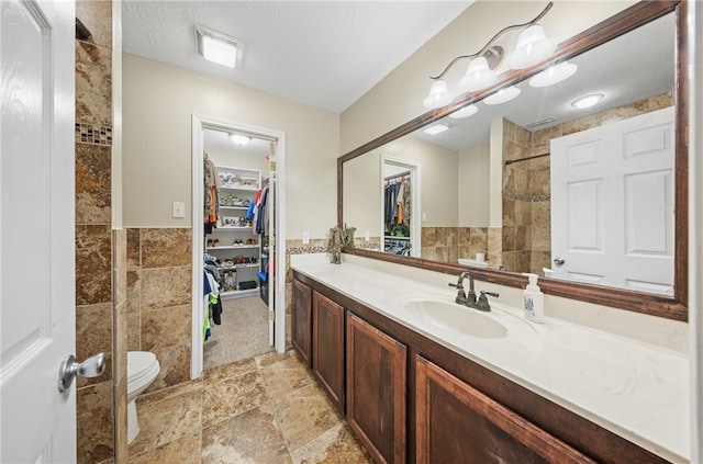 5413 King Trl, Corpus Christi, TX 78414 - bathroom with vanity, toilet, tile walls, a walk in closet, and tiled shower