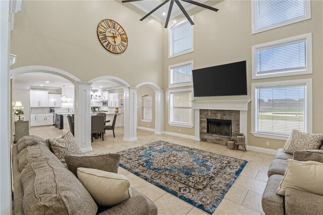 5413 King Trl, Corpus Christi, TX 78414 - living area featuring ornate columns, a towering ceiling, a ceiling fan, a stone fireplace, and light tile patterned floors