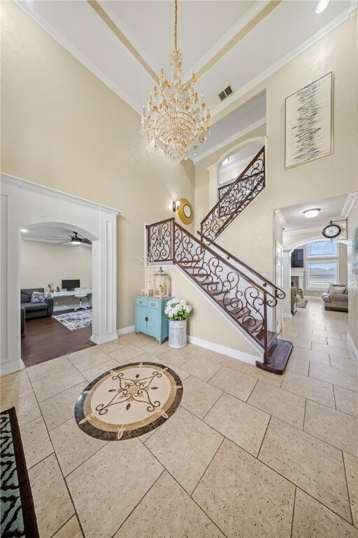 5413 King Trl, Corpus Christi, TX 78414 - foyer featuring a high ceiling, arched walkways, baseboards, inlaid floor details, and a chandelier