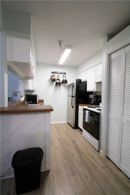 kitchen featuring stainless steel fridge, white range with electric cooktop, white cabinets, kitchen peninsula, and light hardwood / wood-style flooring