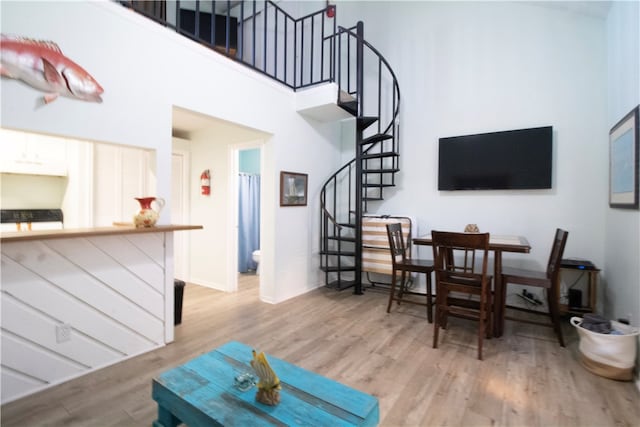 living room featuring a towering ceiling and light hardwood / wood-style flooring