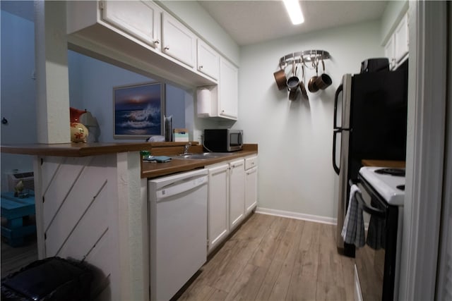 kitchen featuring butcher block counters, sink, light hardwood / wood-style floors, white cabinets, and white appliances