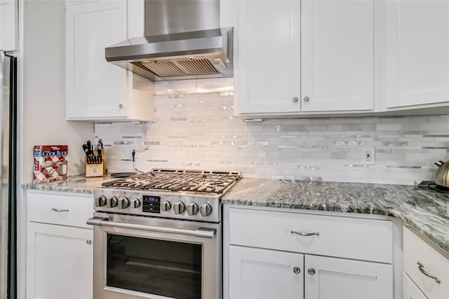 kitchen featuring light stone countertops, stainless steel gas range, range hood, white cabinetry, and backsplash