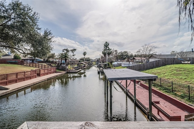 dock area featuring a water view, fence, and a yard