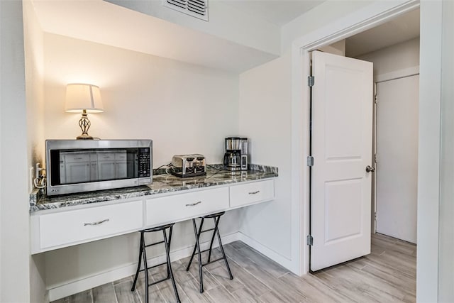 home office featuring baseboards, visible vents, and wood finish floors