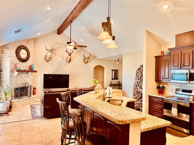 kitchen featuring sink, vaulted ceiling with beams, a kitchen bar, a kitchen island with sink, and appliances with stainless steel finishes