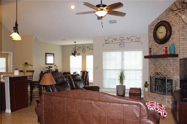 tiled living room with ceiling fan, lofted ceiling, and a brick fireplace