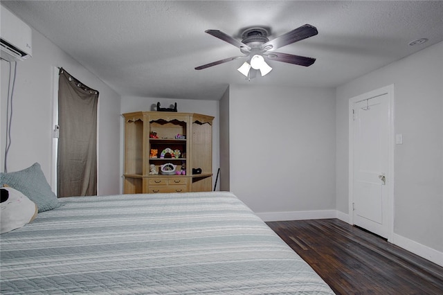 bedroom with ceiling fan, dark hardwood / wood-style floors, a textured ceiling, and a wall mounted air conditioner