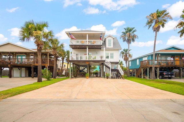 coastal home featuring stairs, a carport, concrete driveway, and a balcony