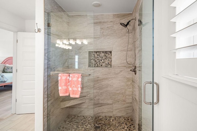 bathroom with connected bathroom, a shower stall, and wood finished floors