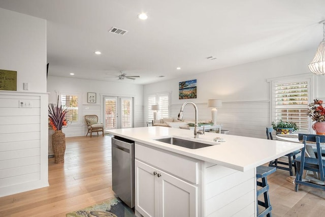 kitchen featuring a center island with sink, visible vents, open floor plan, white cabinetry, and dishwasher