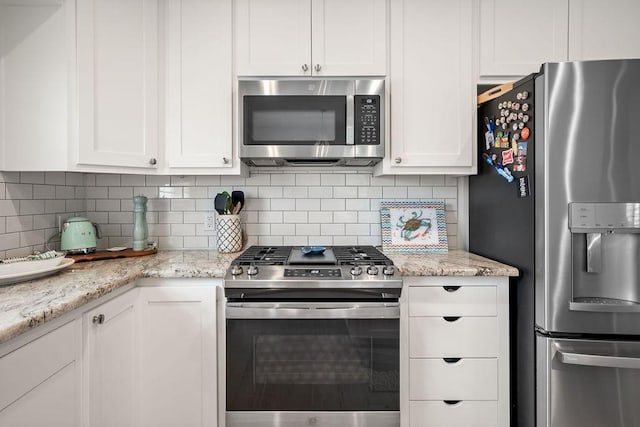 kitchen featuring stainless steel appliances, white cabinetry, and decorative backsplash