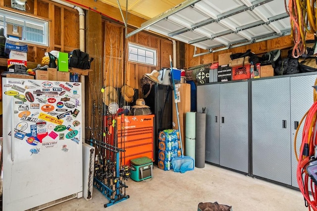 garage with freestanding refrigerator and wooden walls