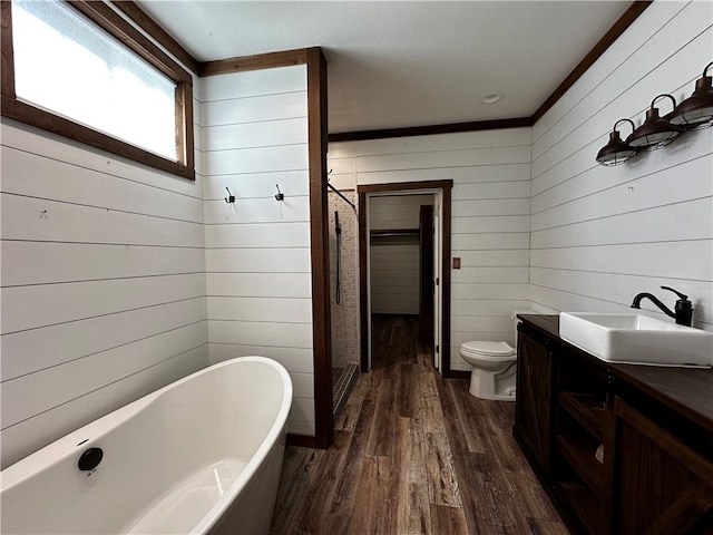 bathroom with a bath, wood-type flooring, vanity, wood walls, and toilet