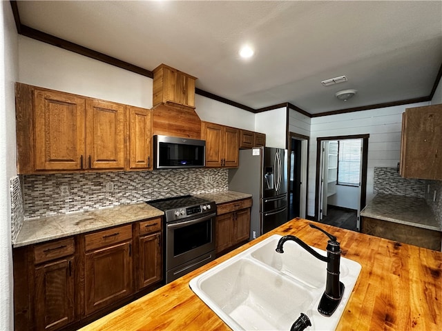 kitchen featuring stainless steel appliances, dark wood-type flooring, sink, ornamental molding, and backsplash