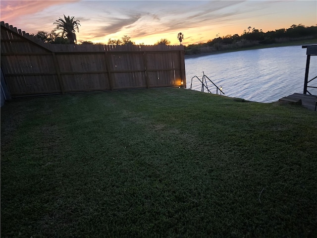 yard at dusk featuring a water view and a boat dock