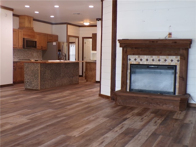 kitchen featuring dark hardwood / wood-style flooring, decorative backsplash, stainless steel fridge, and crown molding