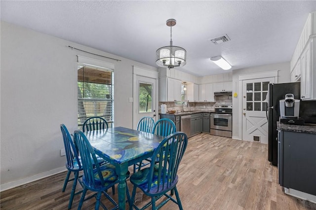 110 Wildwood, Rockport, TX 78382 - dining space with light wood-style flooring, a chandelier, and a textured ceiling