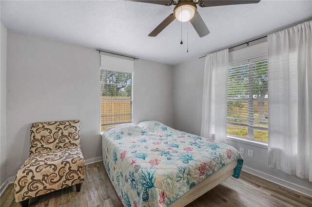 110 Wildwood, Rockport, TX 78382 - bedroom with multiple windows, wood finished floors, a ceiling fan, and a textured ceiling