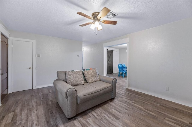 110 Wildwood, Rockport, TX 78382 - living room featuring wood finished floors, a ceiling fan, a barn door, and a textured ceiling