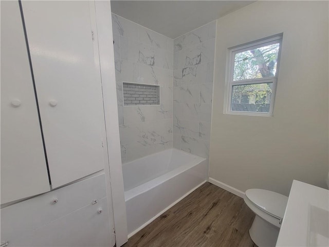 bathroom with hardwood / wood-style floors, tiled shower / bath combo, and toilet