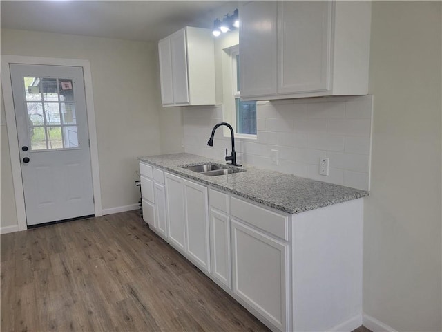 kitchen featuring white cabinets, sink, decorative backsplash, light stone countertops, and light hardwood / wood-style floors