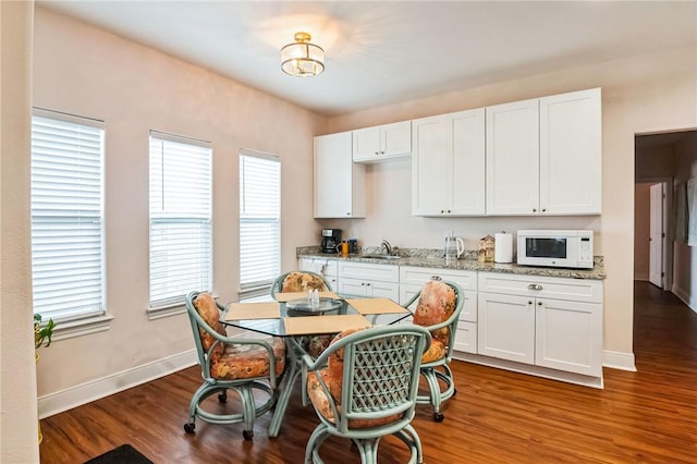 kitchen featuring white cabinetry, dark wood-type flooring, light stone countertops, and sink