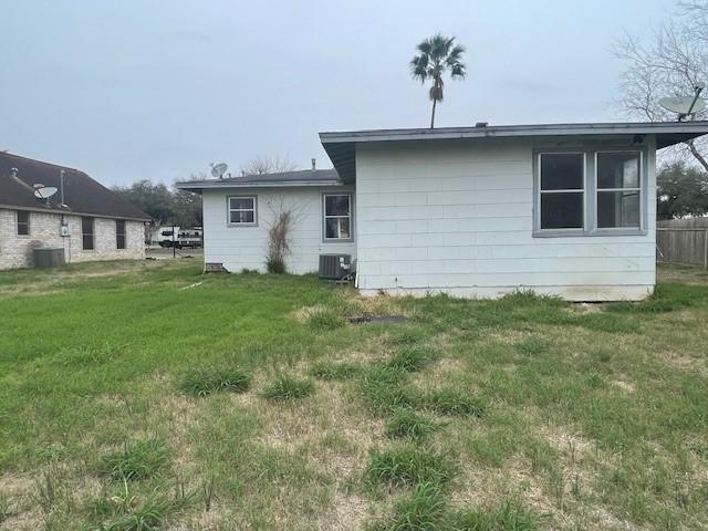 back of property with central AC unit and a lawn