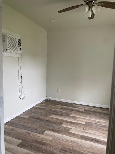 empty room with hardwood / wood-style flooring, an AC wall unit, and ceiling fan