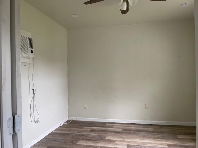 spare room with hardwood / wood-style flooring, a wall mounted AC, and ceiling fan