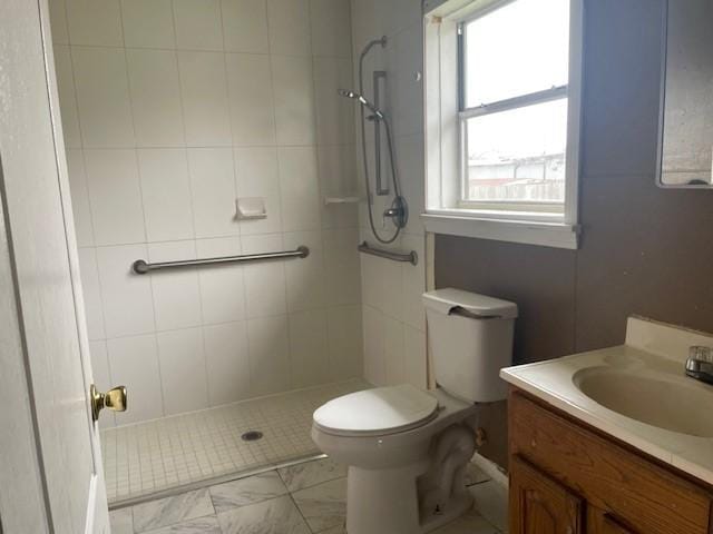 bathroom with vanity, toilet, and a tile shower