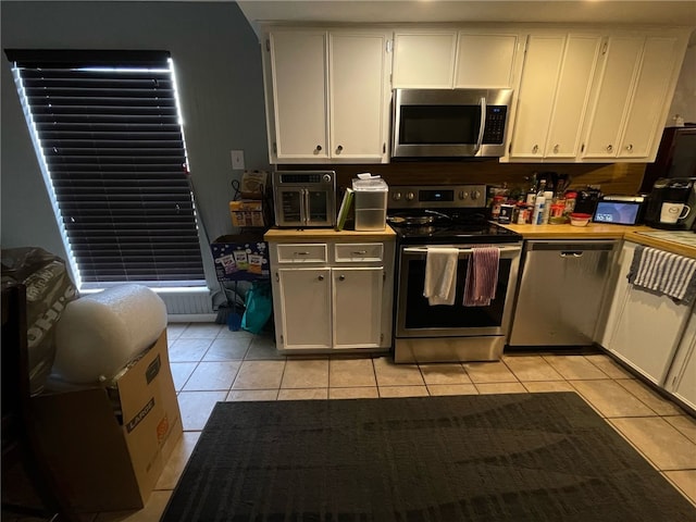 kitchen with white cabinets, stainless steel appliances, and light tile patterned floors
