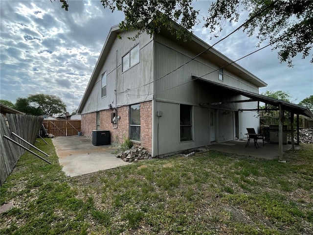 rear view of property featuring a patio area, a lawn, a fenced backyard, and central AC unit
