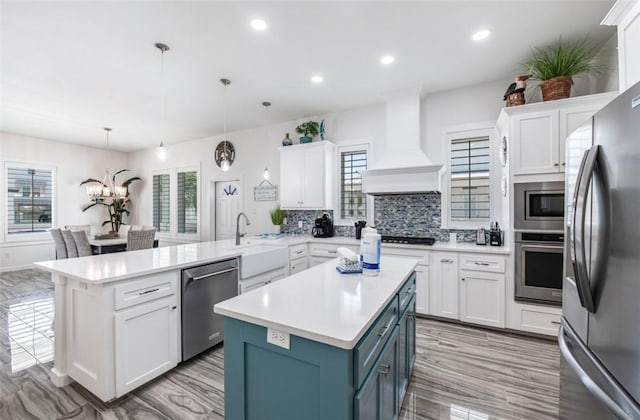 kitchen featuring hanging light fixtures, custom exhaust hood, stainless steel appliances, and white cabinets