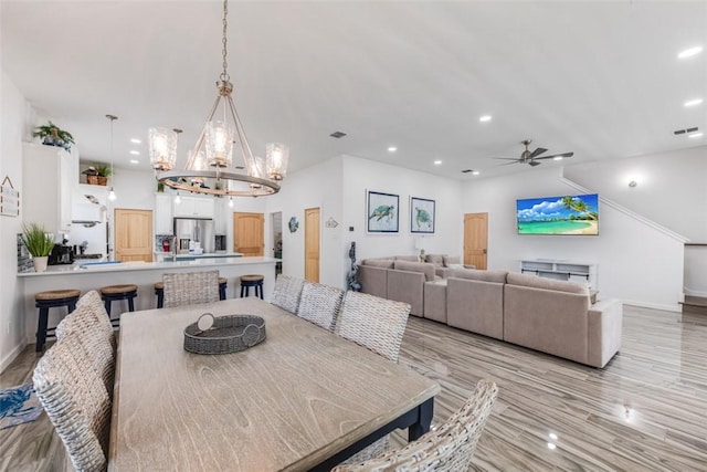 dining room featuring ceiling fan with notable chandelier and light hardwood / wood-style flooring