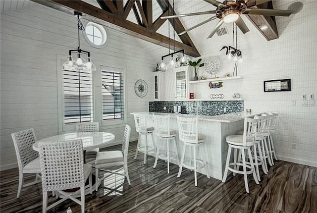 kitchen featuring dark wood-type flooring, a kitchen bar, white cabinetry, decorative light fixtures, and kitchen peninsula