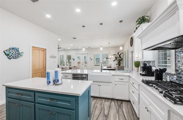 kitchen with sink, light hardwood / wood-style flooring, hanging light fixtures, stainless steel appliances, and white cabinets