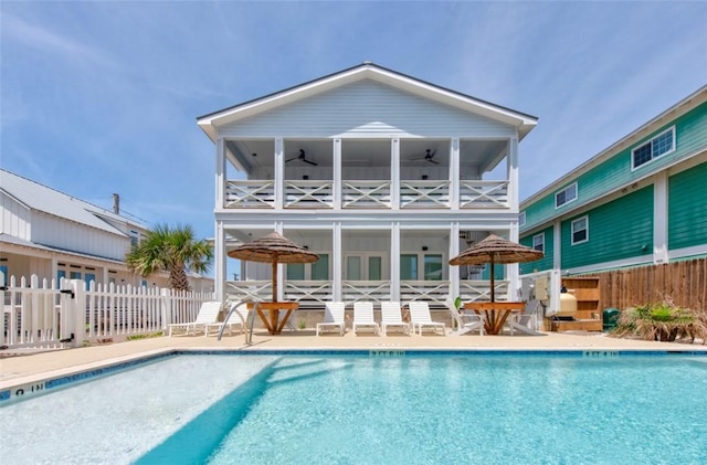 back of property with a balcony, a community pool, ceiling fan, and a patio area