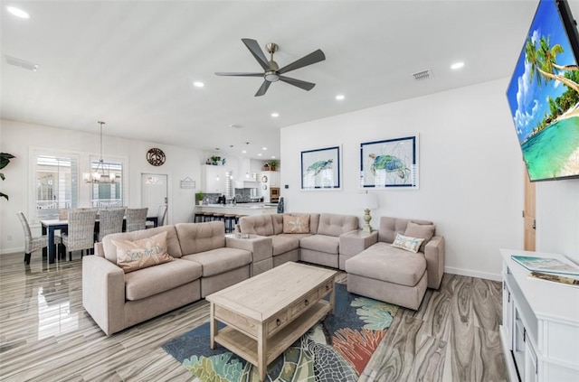 living room featuring ceiling fan with notable chandelier