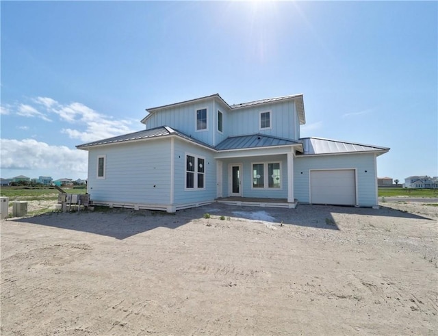7518 Ruby Bay Ct, Port Aransas, TX 78373 - view of front of house with an attached garage, a standing seam roof, dirt driveway, and metal roof
