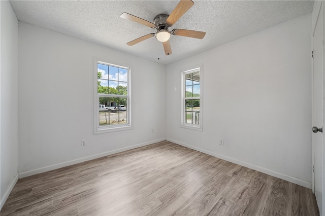 spare room featuring ceiling fan, a textured ceiling, light hardwood / wood-style floors, and plenty of natural light